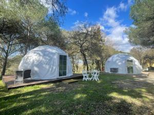 two domed tents in a field with two chairs at Toscana Holiday Village in Montopoli in Val dʼArno