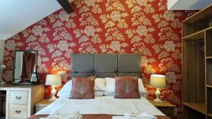 a bedroom with a bed with a red wall at George & Dragon, Conwy in Conwy