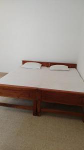 a wooden bed with white sheets on top of it at Rajarata Villa Anuradhapura in Anuradhapura
