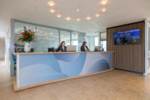deux femmes assises à un comptoir dans un bureau dans l'établissement Hotel de Baak Seaside, à Noordwijk aan Zee