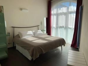 a bed in a room with a large window at Affittacamere Casamatta in La Morra