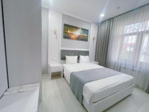 een witte slaapkamer met 2 bedden en een raam bij Moffah Grand Hotel 美华酒店 in Tasjkent