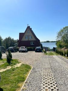 a house with cars parked on the side of a road at Pensjonat Krzyś in Nielisz