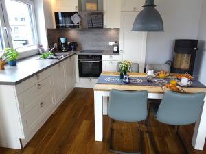 una cocina con armarios blancos y una mesa con sillas azules en Gode Wind Quartiere 6, en Dahme