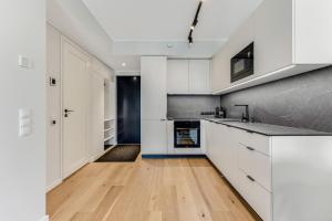 a kitchen with white cabinets and a hardwood floor at 15 korruse premium katusekorter in Tallinn