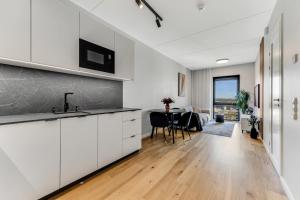 a kitchen with white cabinets and a table with chairs at 15 korruse premium katusekorter in Tallinn