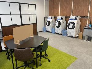 a room with a table and several washing machines at Garden Hotel Matsumoto in Matsumoto