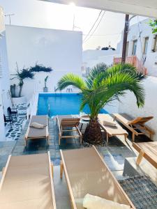 een zwembad met tafels en stoelen en een palmboom bij Kamara Residence & Suites in Mykonos-stad