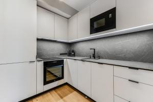 a white kitchen with white cabinets and a sink at 15 korruse premium katusekorter in Tallinn