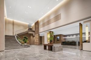 a lobby of a hotel with stairs and potted plants at Atour Hotel Chongqing Liangjiang Happiness Plaza in Chongqing