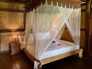 a bedroom with a canopy bed with mosquito nets at Flower Bud Bungalow Balangan in Jimbaran