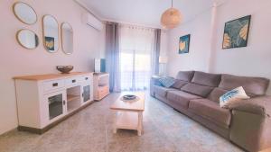 ein Wohnzimmer mit einem Sofa und einem Tisch in der Unterkunft Apartamento muy cerca del mar. in Arenales del Sol