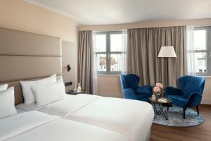 a hotel room with a bed and two blue chairs at NH Berlin Kurfürstendamm in Berlin