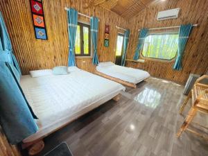 two beds in a room with wooden floors and windows at Bamboo Eco Lodge - Venuestay in Mai Chau