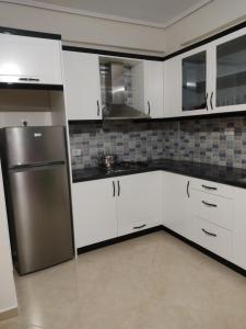 cocina con armarios blancos y nevera de acero inoxidable en Lukova Center Apartments, en Lukovë