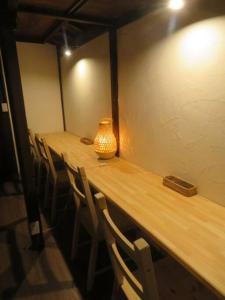 un lungo tavolo in legno con sedie e un vaso sopra di 昭和レトロが息づく狐白庵 a Nagano