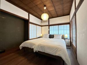 una camera da letto con un grande letto con lenzuola bianche e finestre di 昭和レトロが息づく狐白庵 a Nagano