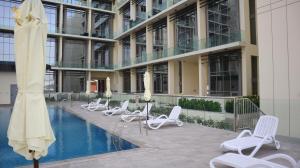 a hotel with chairs and a pool in front of a building at City Chic: Elegant 1BR Apartment in Abu Dhabi