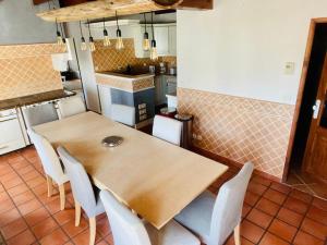 eine Küche mit einem Holztisch und weißen Stühlen in der Unterkunft Maison très agréable et familiale Saintes Royan in La Jard
