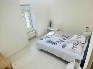 ein weißes Bett in einem weißen Zimmer mit Fenster in der Unterkunft Maison très agréable et familiale Saintes Royan in La Jard