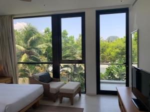 a room with a bed and a tv and windows at Beachview 3BR Villa with private pool in Danang