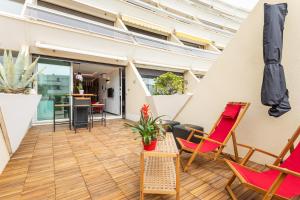 un patio avec des chaises, une table et un parasol dans l'établissement Bambou Heliopolis, au Cap d'Agde