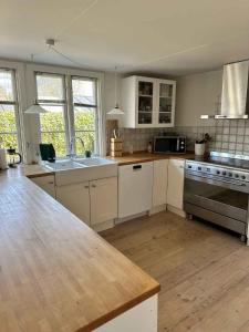 a kitchen with white cabinets and a wooden counter top at Lovely Bright Summer House Close To Hornbæk, in Hornbæk