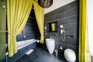 a bathroom with a tub and a toilet and yellow curtains at Hotel Goldene Spinne in Vienna
