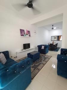 a living room with two blue couches and a tv at Amaris Homestay in Sungai Petani