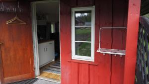 a red door and a window on a house at Riverside Bliss - Cozy Cabin near Tvedestrand with WiFi and Deck in Vegårshei
