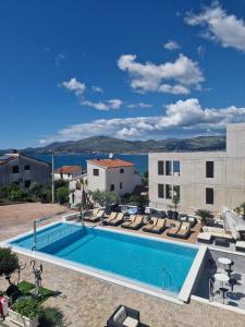 a swimming pool with lounge chairs next to a building at Apartments Silva in Trogir