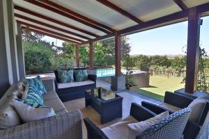 a screened in porch with couches and a pool at Aloe Arbour Self-catering cottages in White River