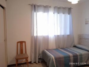 a bedroom with a window with a bed and a chair at Apartamento Caños de Meca in Los Caños de Meca +21 photos