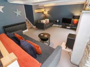 een woonkamer met een bank en een televisie bij Winterbrook Cottage in St Austell