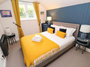 een slaapkamer met een bed met een gele deken bij Winterbrook Cottage in St Austell