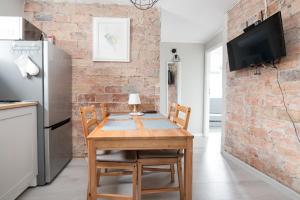 una cucina con tavolo in legno e muro di mattoni di Koliber by 3City Rentals a Gdynia