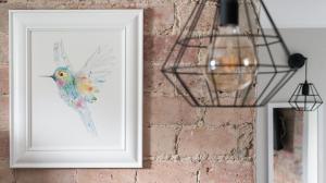 a picture of a bird in a white frame on a brick wall at Koliber by 3City Rentals in Gdynia