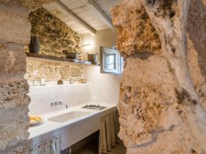 La salle de bains est pourvue d'un lavabo et d'un mur en pierre. dans l'établissement Masseria de Li Travaj by RivedelSalento, à Patù