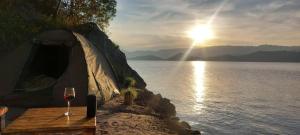 szklankę wina siedzącą obok namiotu nad wodą w obiekcie FRAMA ECO LODGE, Twin Lakes (big island)- Lake Burera 