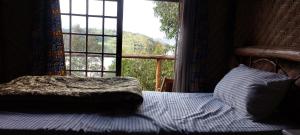 a bedroom with a bed in front of a window at FRAMA ECO LODGE, Twin Lakes (big island)- Lake Burera 