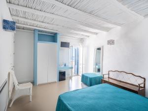 a white room with a bed and a chair at Tannur B&B in Castellammare del Golfo