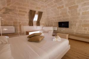 una camera con un grande letto bianco e un divano di Antica Dimora Storica La Finestra Sul Campanile a Matera