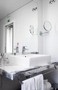 a white bathroom with a sink and a mirror at Rio Art Hotel in Setúbal