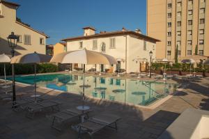 a pool with chairs and umbrellas in front of a building at Villa Carobbi Apartments Florence in Florence +49 photos