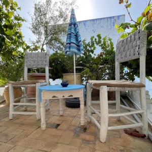 una mesa y 2 sillas y una sombrilla en el patio en RIAD OASIS D'ASILAH en Asilah