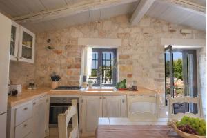 a kitchen with white cabinets and a stone wall at Trulli Dimore - Trulli della Lama in Castellana Grotte
