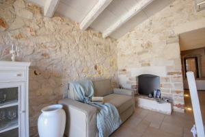 a living room with a couch and a stone wall at Trulli Dimore - Trulli della Lama in Castellana Grotte