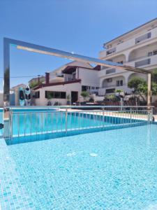 a swimming pool with a blue fence and some buildings at Apartments Silva in Trogir