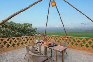 einen Tisch und Stühle auf einem Balkon mit Aussicht in der Unterkunft Chahal Tree Farm House - 20 min Ride from Golden Temple in Amritsar