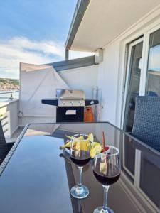 - deux verres de vin sur un balcon avec barbecue dans l'établissement Apartments Silva, à Trogir